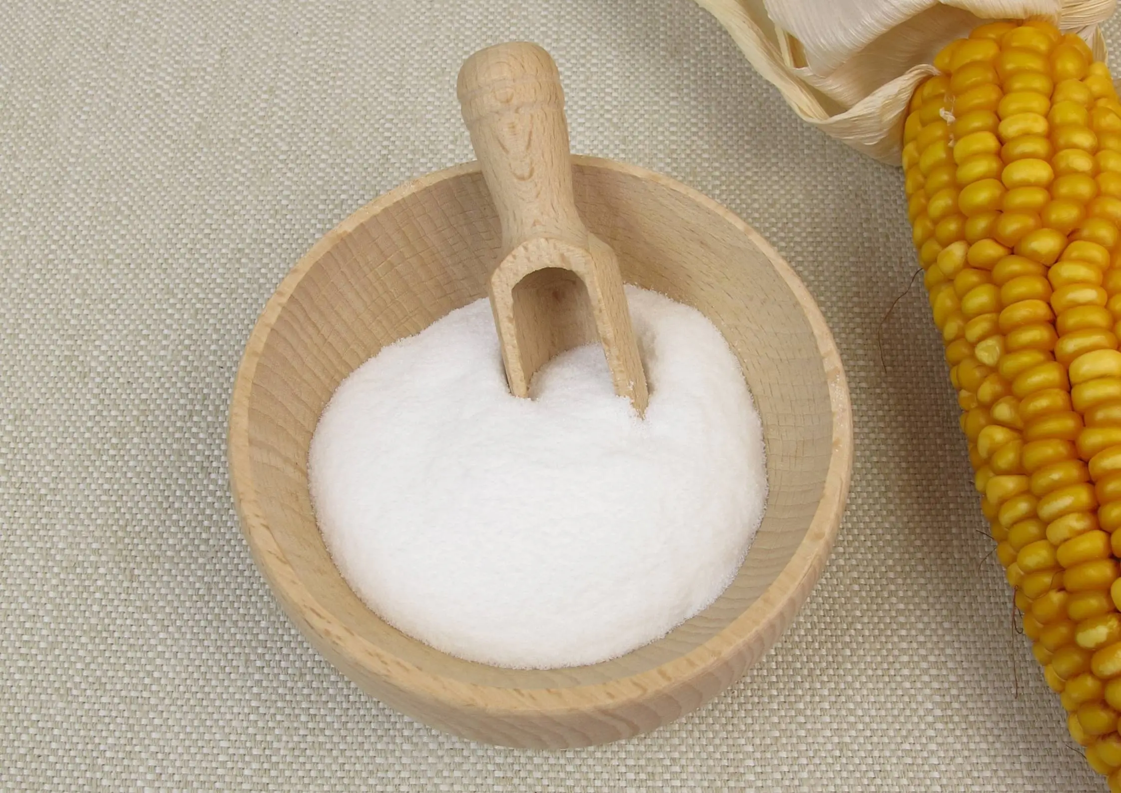 Dextrose powder in a wooden bowl with corn and potatoes