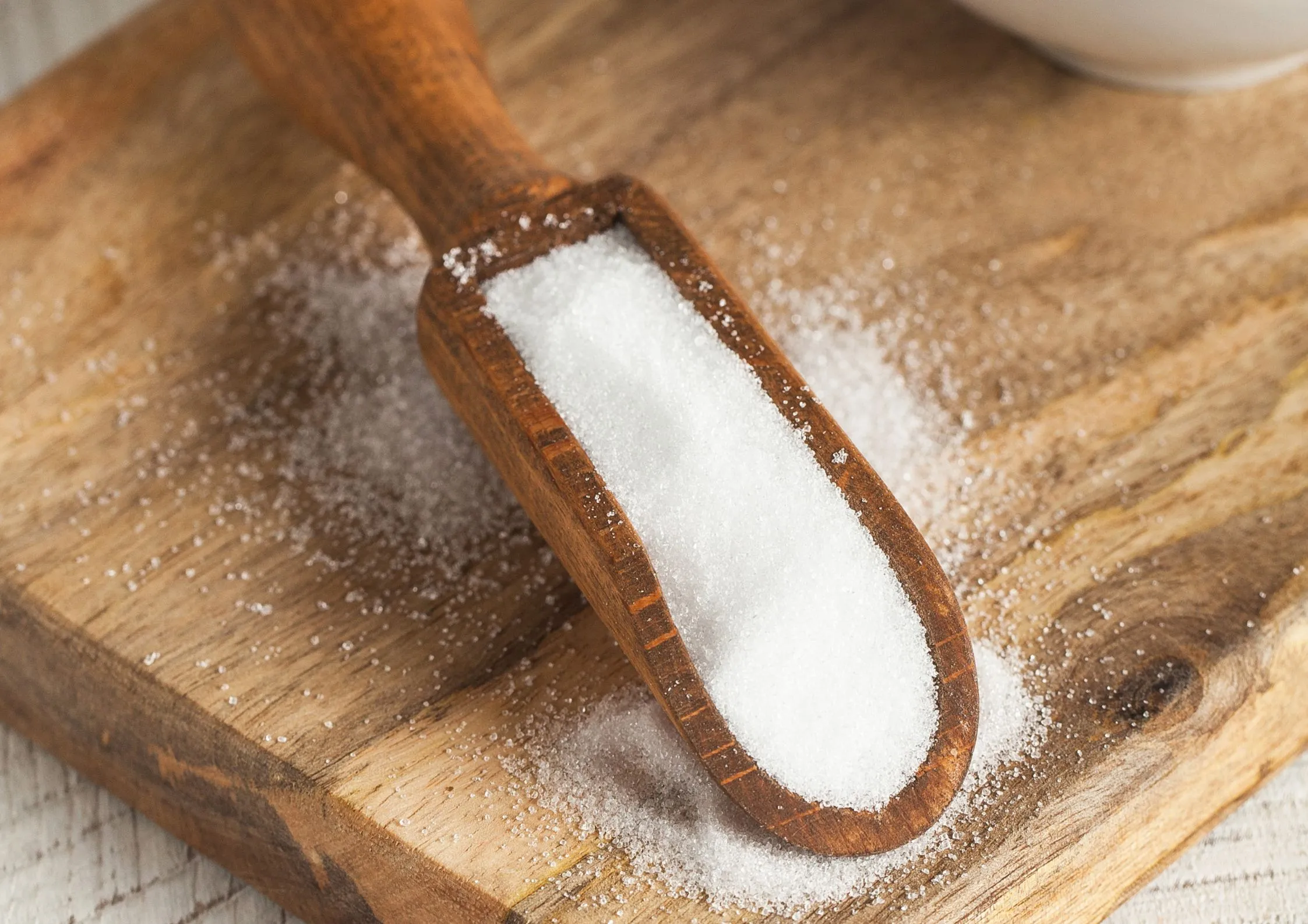 Erythritol powdered sugar in a wooden scoop on a rustic board, perfect for dusting and decorative use.