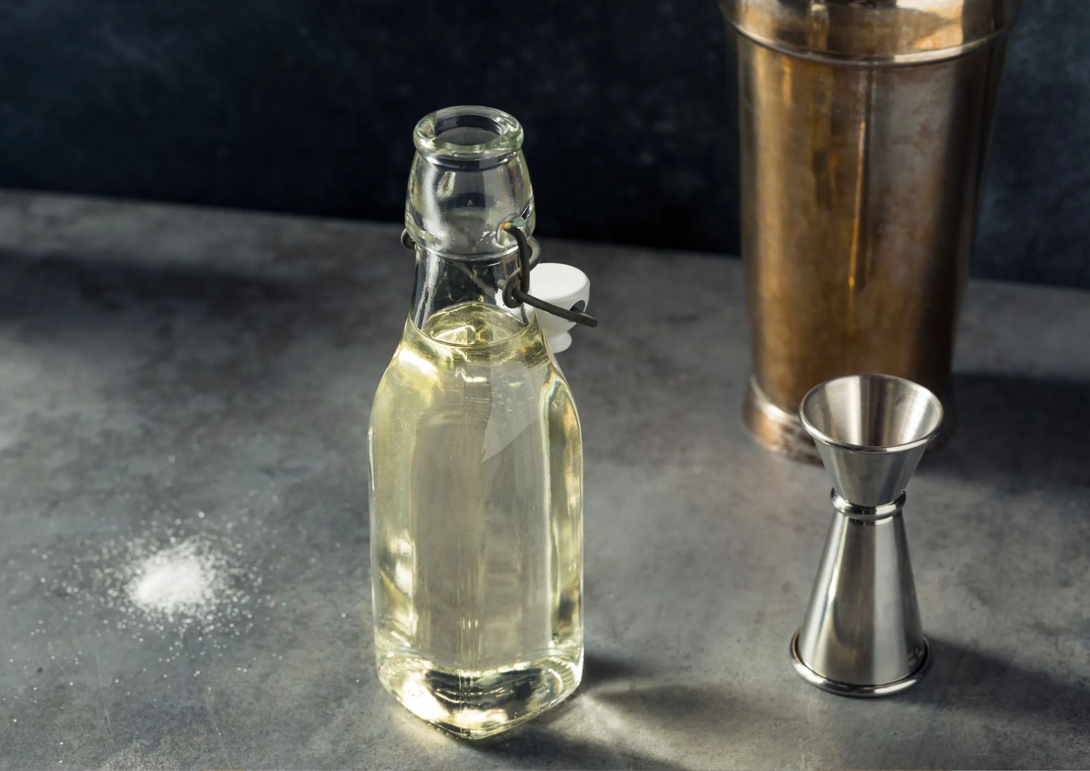 Clear glass bottle filled with liquid sucrose on a dark countertop.