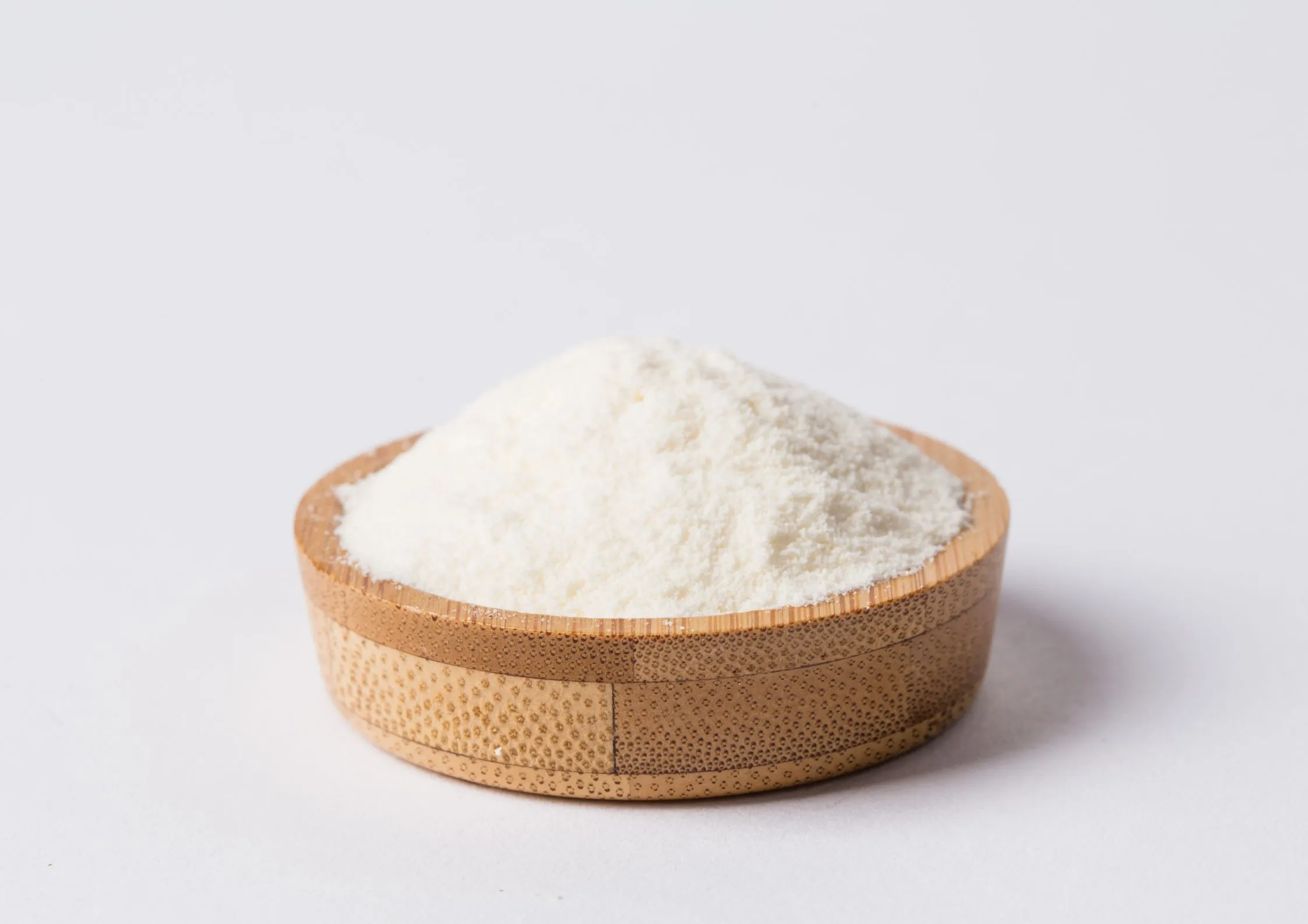 Fine white maltitol powder in a small wooden bowl, ideal for low-calorie baking and candy making.