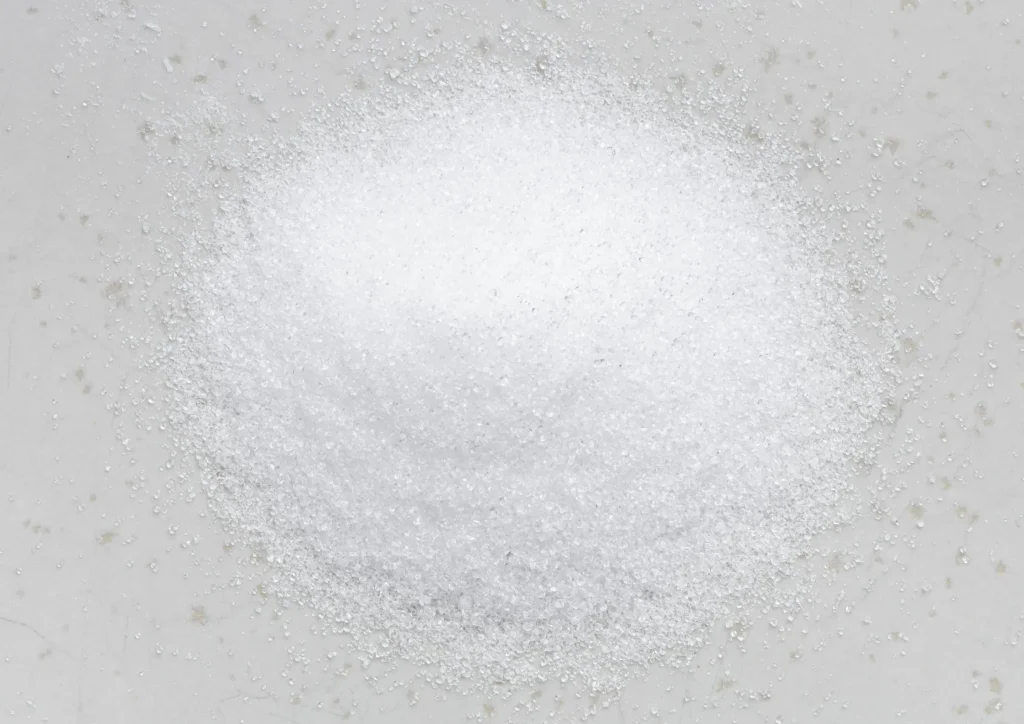 Fine white powdered erythritol scattered on a smooth surface, ideal for low-calorie recipes and sweetening.